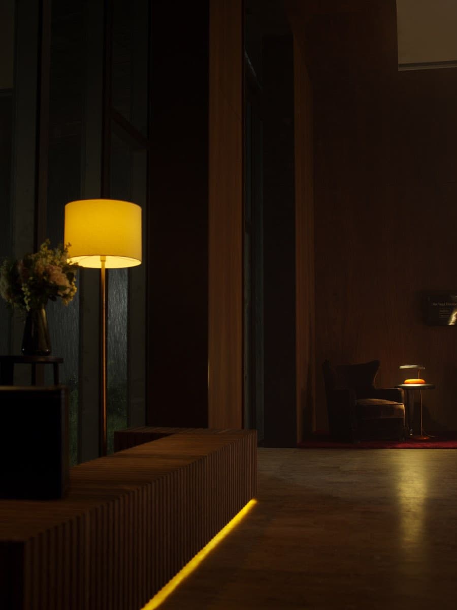 Lobby d'hôtel au crépuscule, lampe ambre et fauteuil de velours