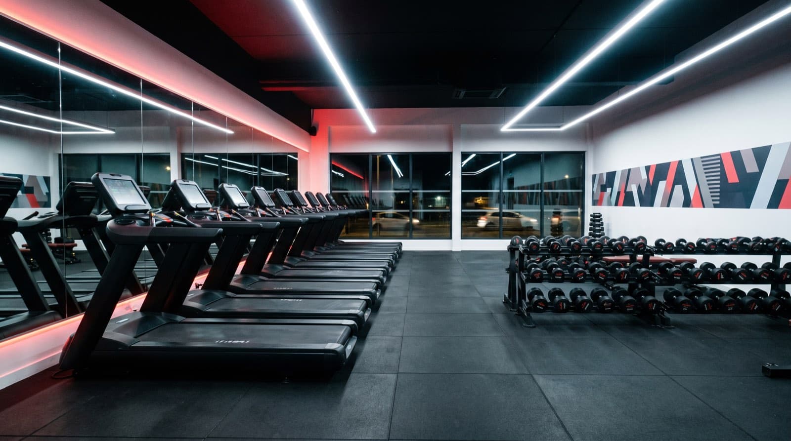 Salle de sport de chaîne, tapis de course alignés face aux miroirs, liseré rouge